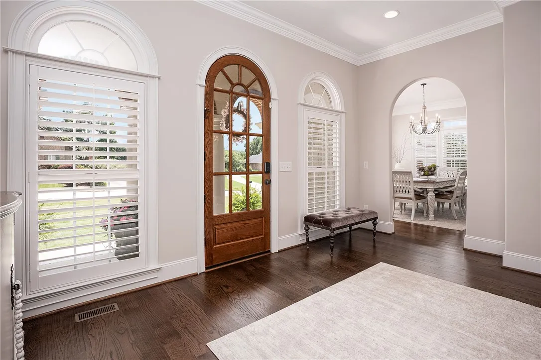 An inviting foyer welcomes with polished hardwood floors and an elegant arched entryway.