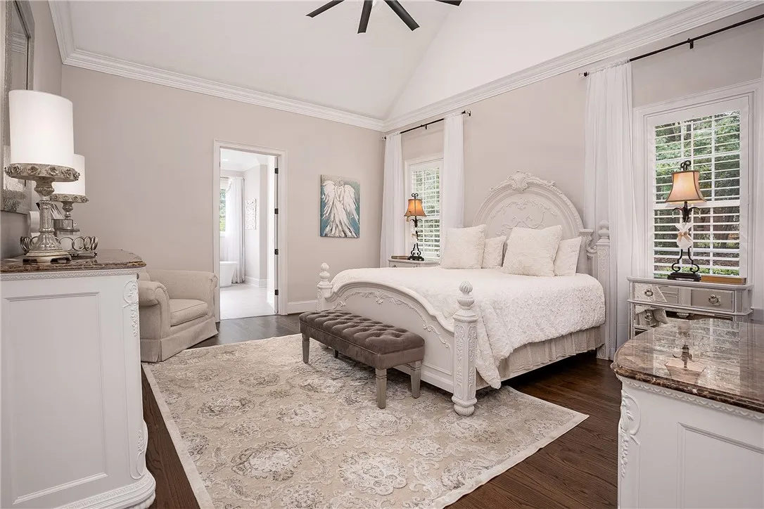 Elegant primary bedroom offers vaulted ceilings and a clear view into a luxurious en-suite bathroom.