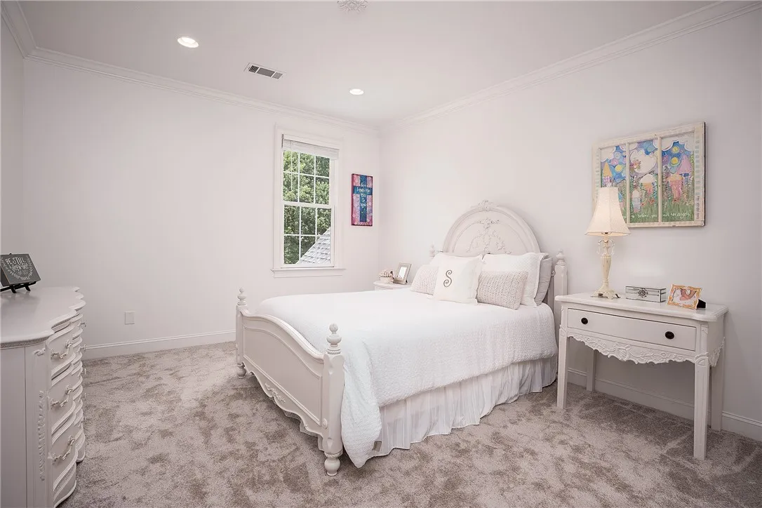 Recessed lighting illuminates this tranquil bedroom with plush carpet and ample natural light from a window.