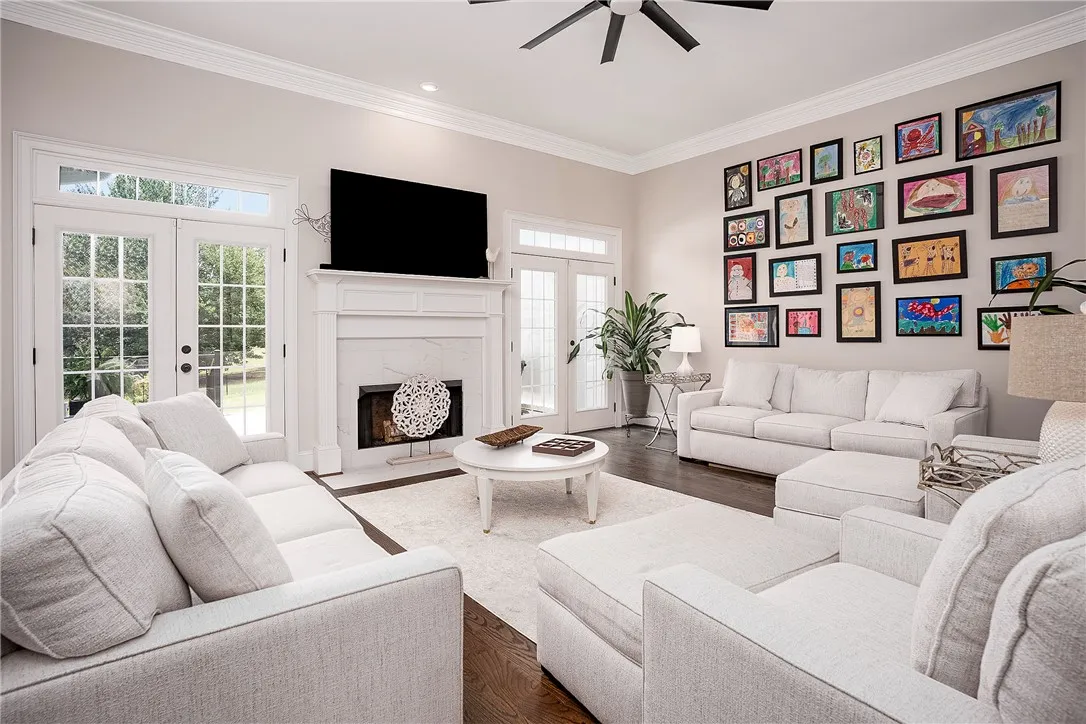 French doors and a marble fireplace anchor this spacious living area, offering elegant comfort and a garden view.