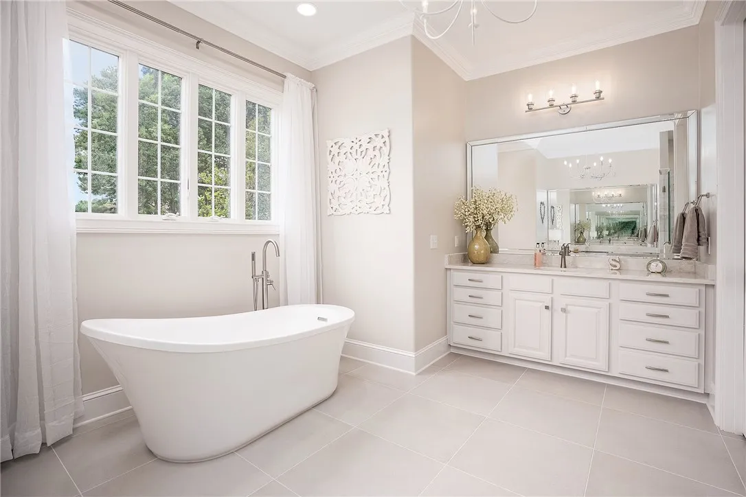 Luxurious bathing retreat boasts a freestanding tub, dual vanity, and sun-drenched window.