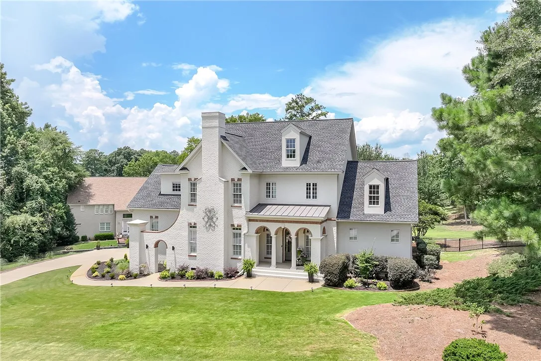 A stately manor with a grand arched entry and meticulously manicured grounds invites luxurious living.
