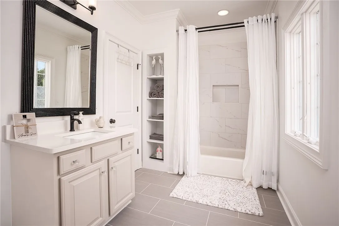 A well-appointed bathroom features a single vanity, ample storage, and a pristine shower with tiled walls.