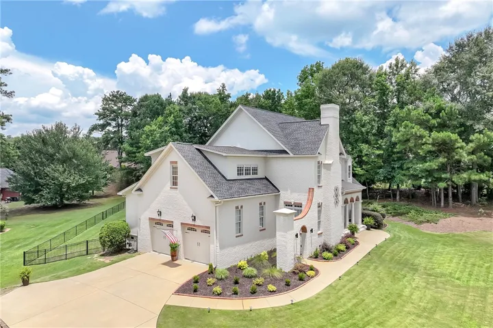 White brick residence with a neatly manicured landscape and a spacious driveway.
