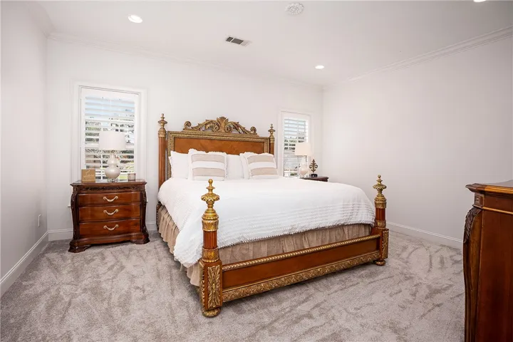 Plush carpeting and crown molding enhance this comfortable primary bedroom.