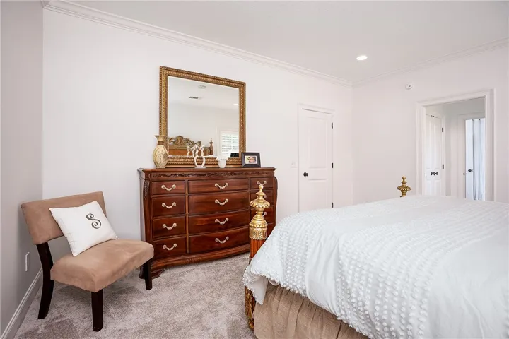 Well-lit bedroom offers carpeted flooring and subtle crown molding details.