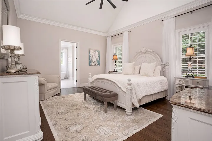 Elegant primary bedroom offers vaulted ceilings and a clear view into a luxurious en-suite bathroom.
