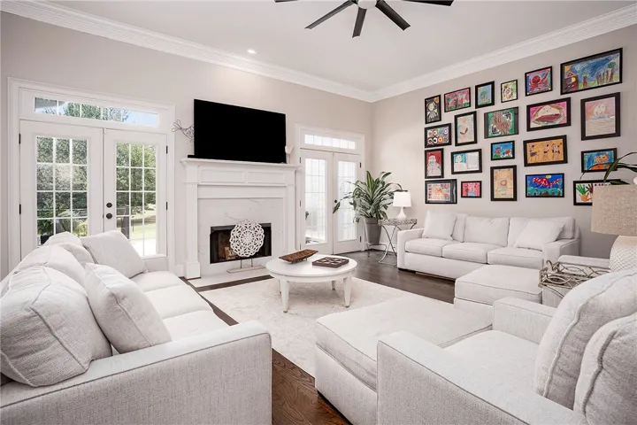 French doors and a marble fireplace anchor this spacious living area, offering elegant comfort and a garden view.