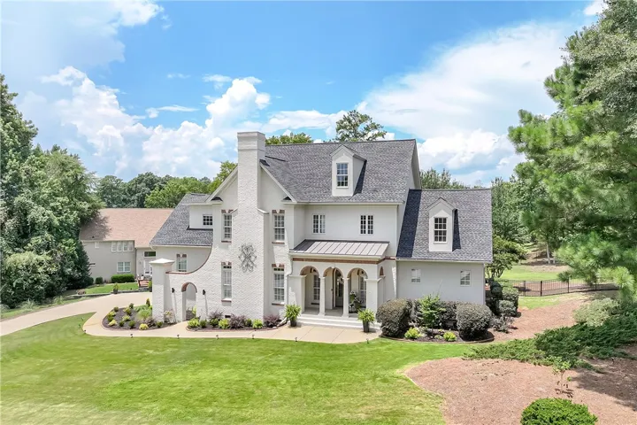 A stately manor with a grand arched entry and meticulously manicured grounds invites luxurious living.