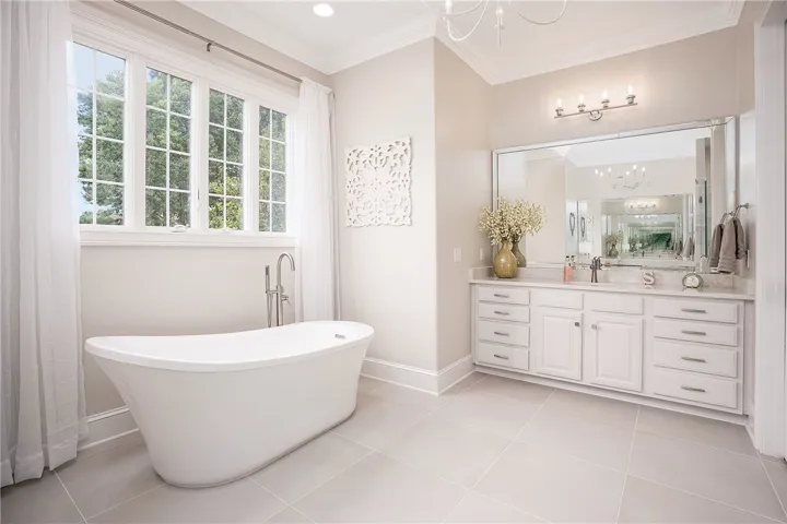 Luxurious bathing retreat boasts a freestanding tub, dual vanity, and sun-drenched window.