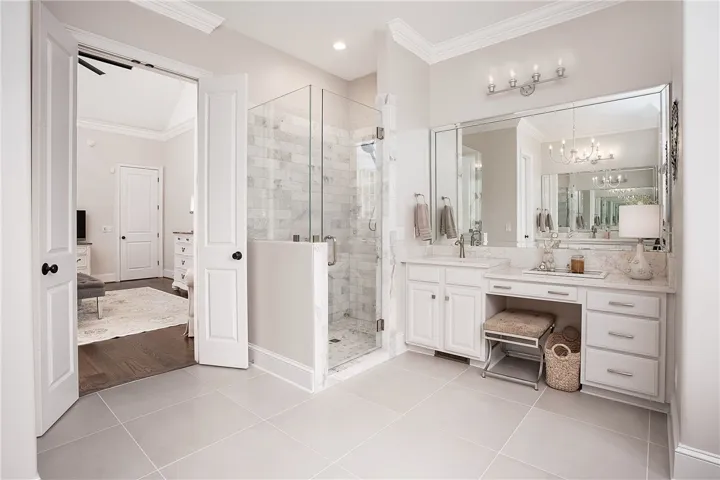 Marble accents and crown molding elevate this master bathroom, featuring a glass-enclosed shower and dual vanity.