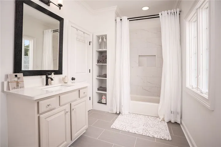 A well-appointed bathroom features a single vanity, ample storage, and a pristine shower with tiled walls.