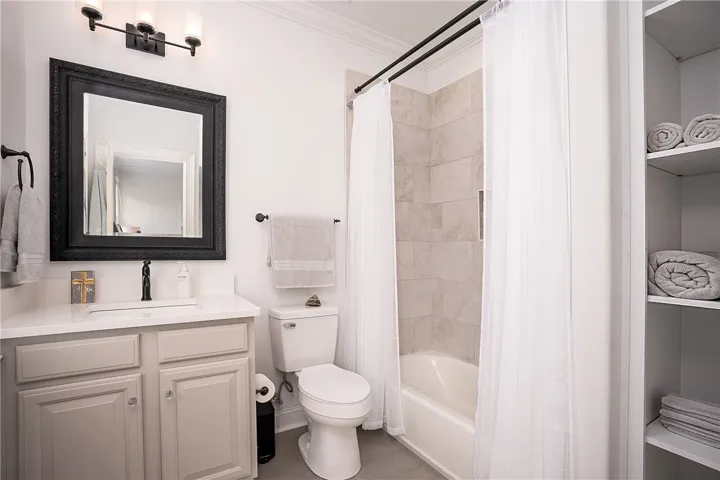 A refined bathroom featuring clean lines, a vanity with ample storage, and a shower-tub combination.
