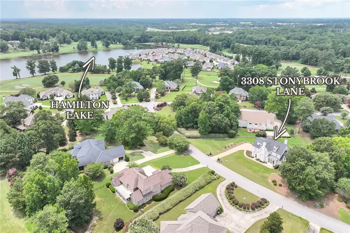 An aerial perspective reveals a serene community with ample green space and nearby lake views.