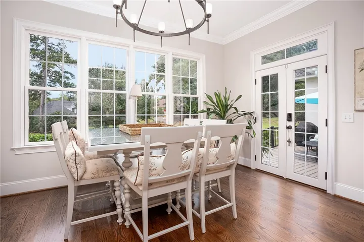 Hardwood floors and generous windows illuminate this welcoming dining area, offering a pleasant view.