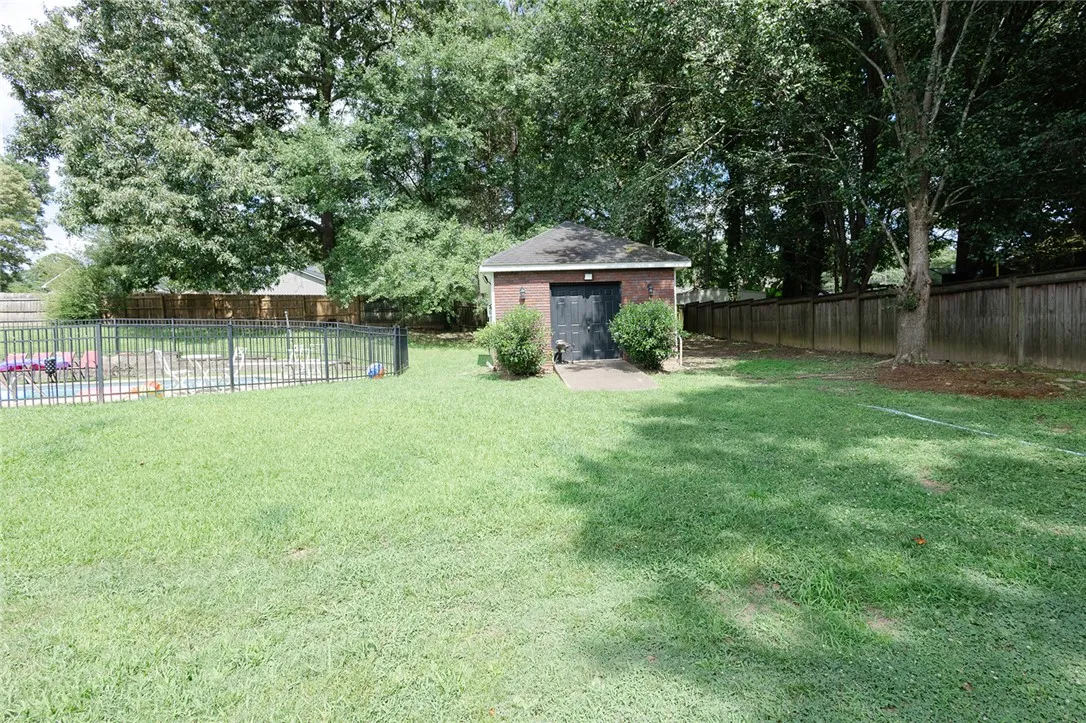A spacious backyard features a brick outbuilding, fenced swimming pool, and mature trees.