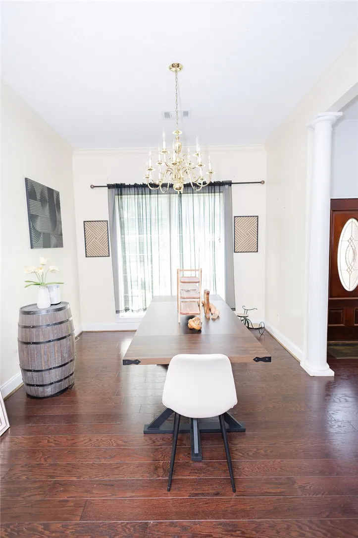 A grand chandelier illuminates this formal dining area, featuring rich hardwood flooring and crown molding.
