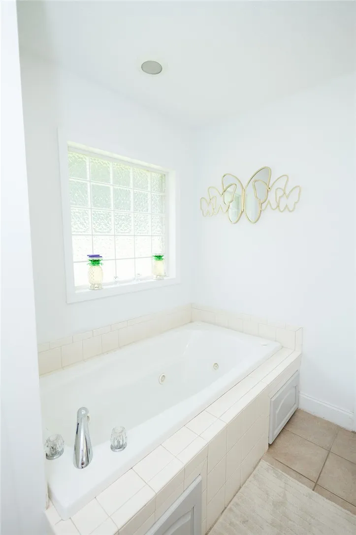 Relax in this inviting soaking tub, complete with a tiled surround and an elegant glass block window.