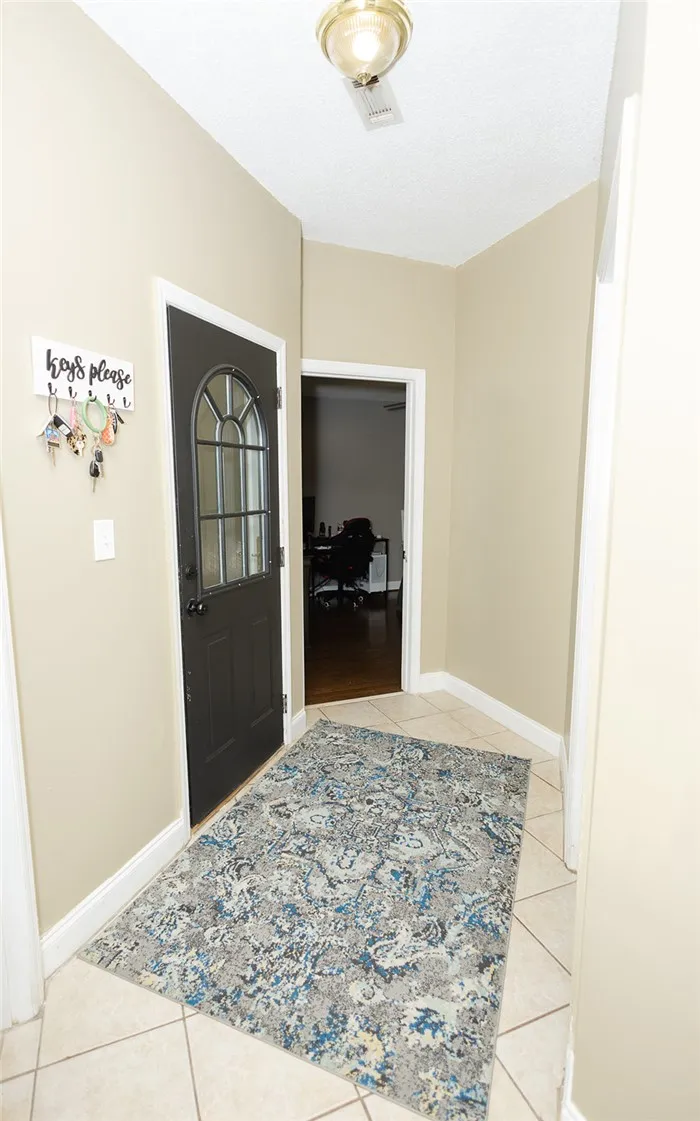 Welcome guests to a tiled entrance foyer with an elegant glass-paneled door.