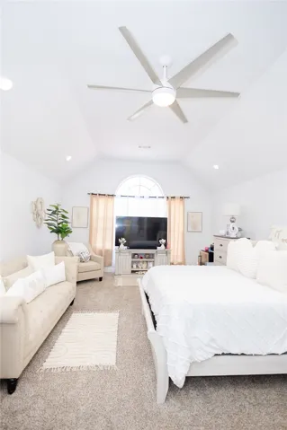 Soaring vaulted ceilings and a grand arched window illuminate this inviting primary bedroom suite.