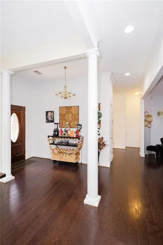 Rich hardwood floors welcome you into this inviting entry with stately columns and an elegant chandelier.