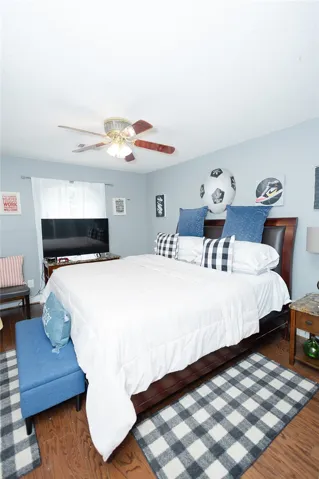 Hardwood floors and a ceiling fan enhance this naturally lit bedroom.