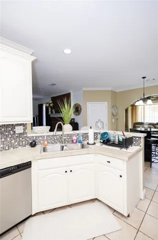 A well-appointed kitchen showcasing a stainless steel sink and a mosaic tile backsplash.