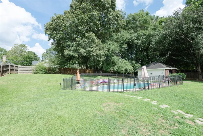 A spacious backyard oasis features a fenced-in pool area, perfect for summer relaxation.