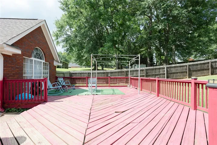 A spacious wooden deck with bright red railings extends from a brick home, offering ample outdoor living space.