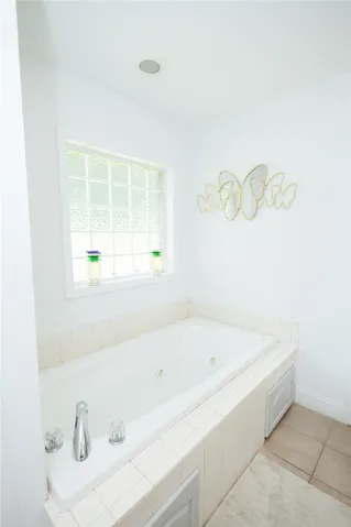 Relax in this inviting soaking tub, complete with a tiled surround and an elegant glass block window.