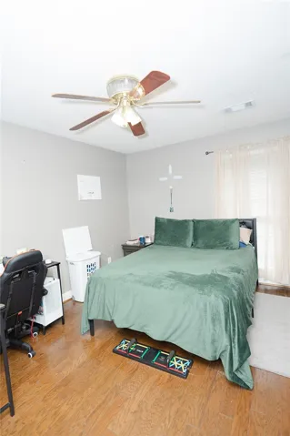 Hardwood floors and a ceiling fan create a comfortable and inviting bedroom retreat.