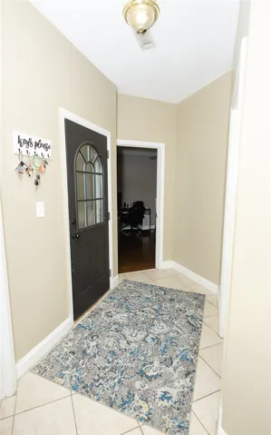 Welcome guests to a tiled entrance foyer with an elegant glass-paneled door.
