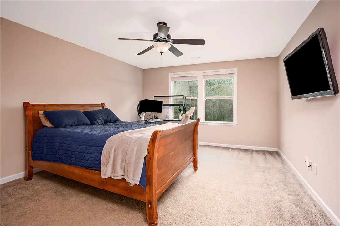 A tranquil bedroom retreat features soft carpeting and a window overlooking lush greenery.