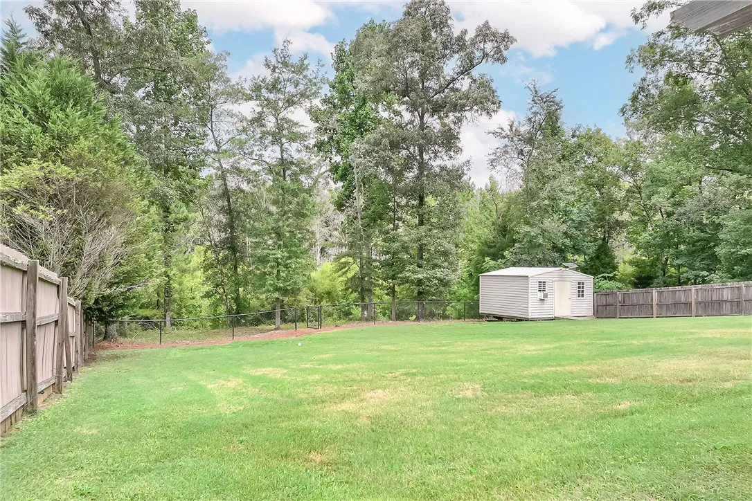 A spacious backyard features a storage shed and a blend of privacy fences.