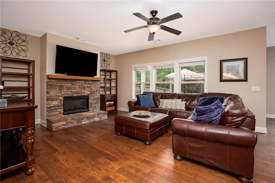 A comforting living area features a stone fireplace, lustrous wood floors, and abundant natural light.