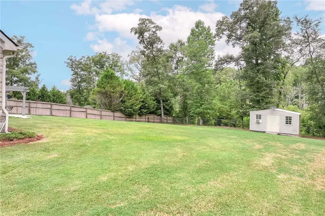 A spacious backyard provides ample green space, secured by a privacy fence, and includes a practical storage shed.