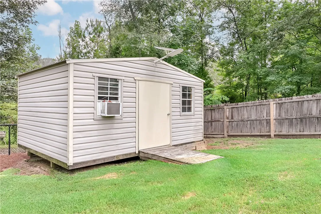 A convenient shed provides ample outdoor storage, nestled beside a wooden privacy fence.