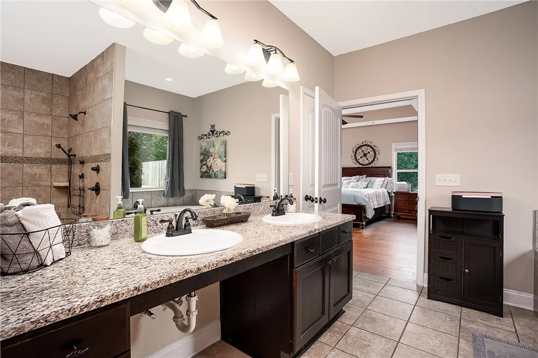 Double vanities and a tiled shower offer comfort in this well-appointed bath adjoining the bedroom.