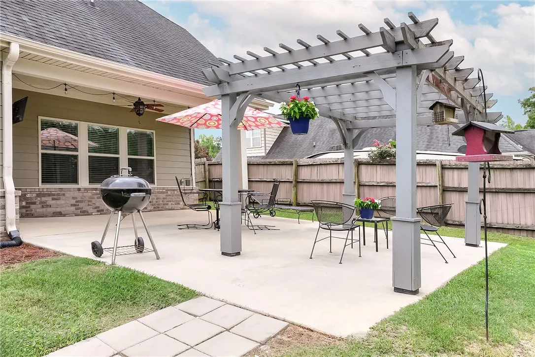An inviting backyard oasis offers a pergola-covered patio perfect for outdoor enjoyment and dining.