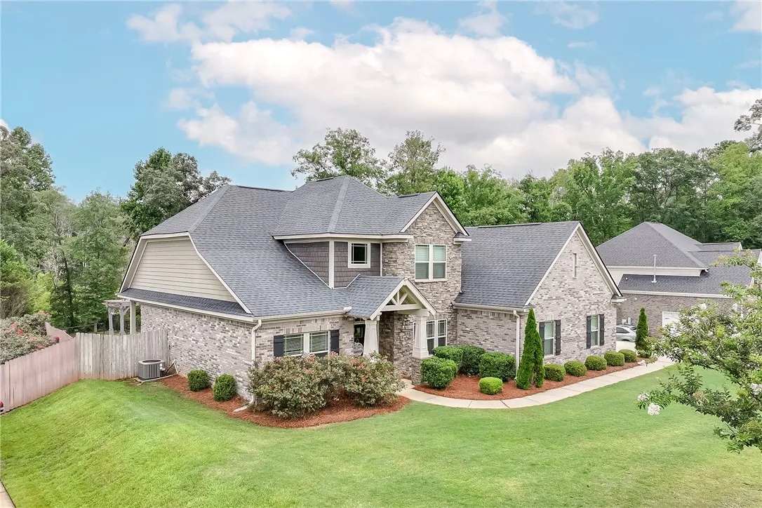 A classic brick and stone residence, framed by mature trees, boasts a neatly landscaped front yard.