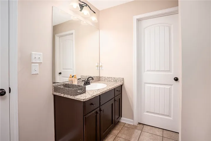 A compact and functional bathroom vanity features a stone counter and ample mirror space, perfect for daily routines.