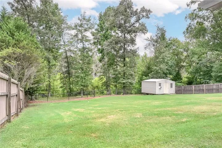 A spacious backyard features a storage shed and a blend of privacy fences.