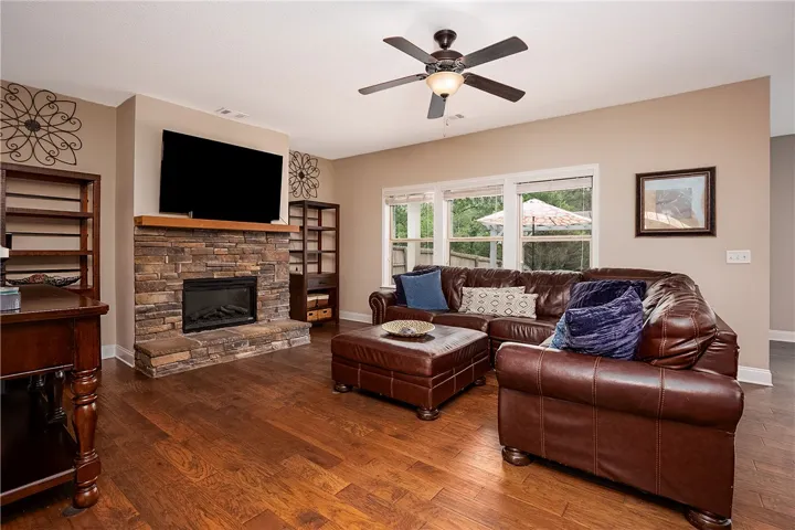 A comforting living area features a stone fireplace, lustrous wood floors, and abundant natural light.