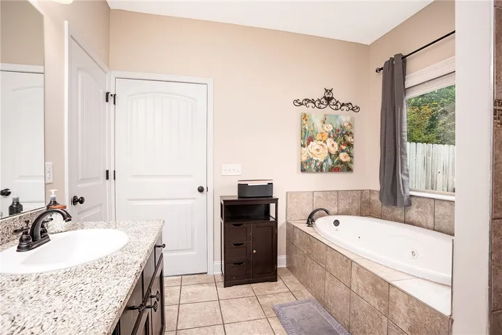 Granite counters and tiled flooring outfit this functional and well-appointed primary bathroom.