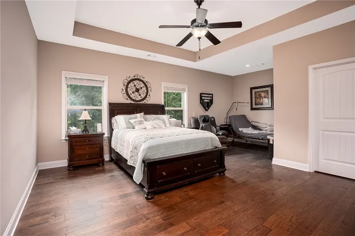 Rich hardwood flooring and tray ceilings enhance the allure of this comfortable bedroom.