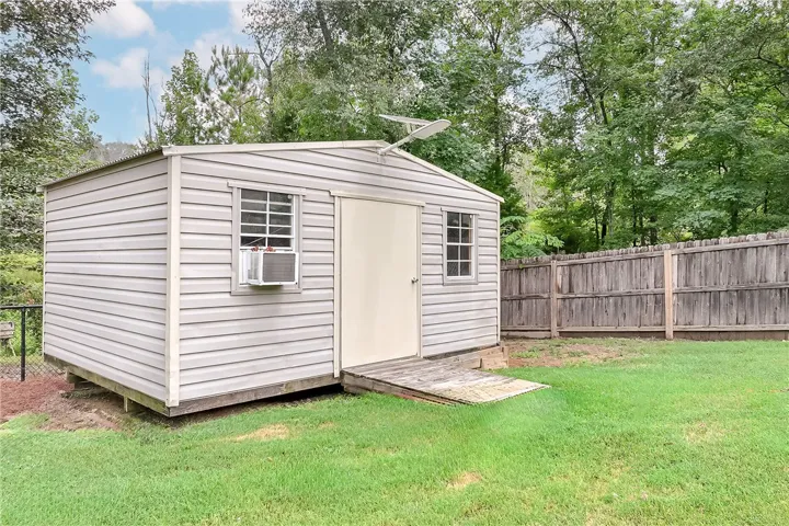 A convenient shed provides ample outdoor storage, nestled beside a wooden privacy fence.