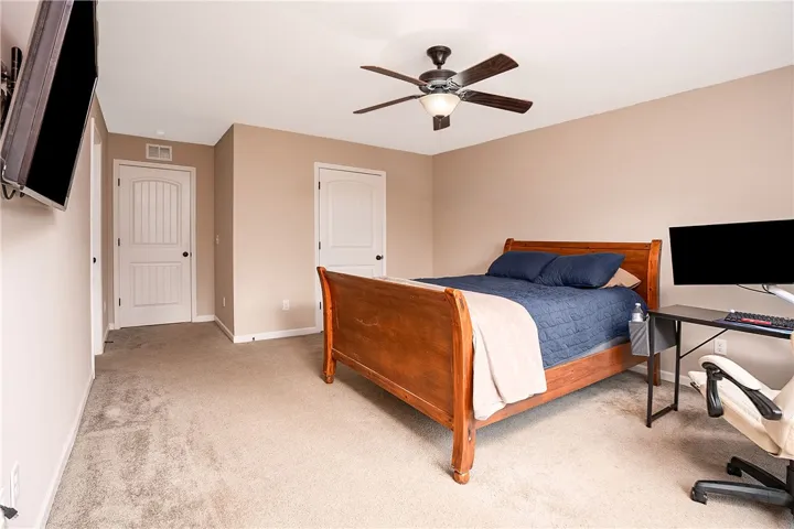 A well-appointed bedroom featuring a ceiling fan and soft carpeting throughout.