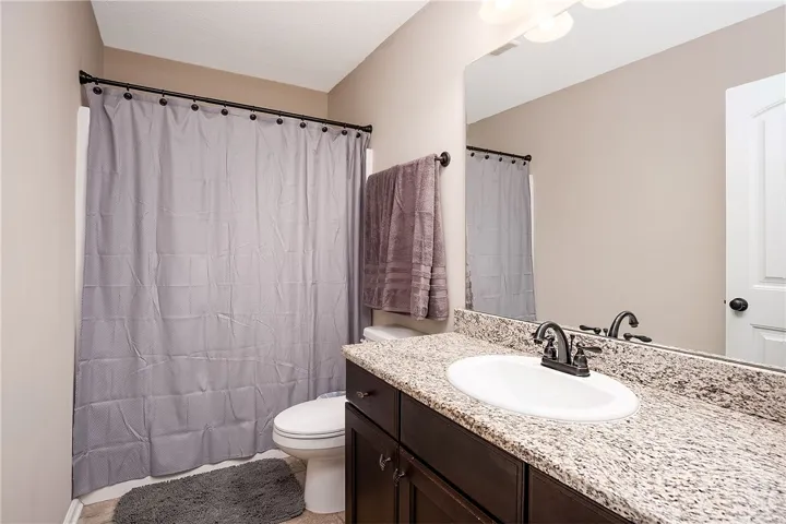Functional full bathroom with granite counters and a practical vanity.