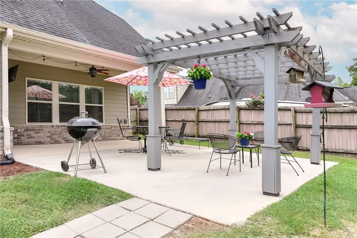 An inviting backyard oasis offers a pergola-covered patio perfect for outdoor enjoyment and dining.
