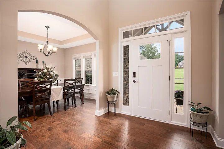 Rich hardwood flooring guides you from the entry to an elegant dining space, defined by an arched doorway and a tray ceiling.